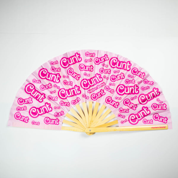 A Bamboo & Silk handheld folding fan that is pink with a hot pink print that says cunt, is spread open on a white background.