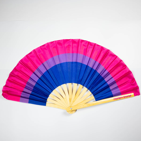 A Bamboo & Silk handheld folding fan that is pink, purple and blue in a bisexual flag design print, is spread open on a white  background.